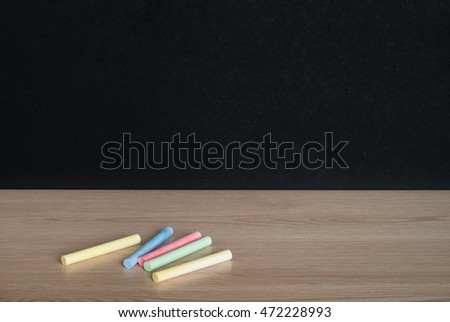 Colored Chalks on classroom table in front of blackboard. View with copy space