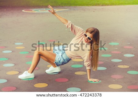 Happy girl playing twister game outdoor Royalty-Free Stock Photo #472243378