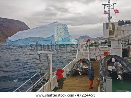a cruise ship approaches a giant iceberg with tourists taking pictures in greenland
