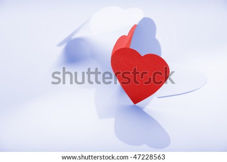Photo of white paper hearts in chain with one of them red being over the others.