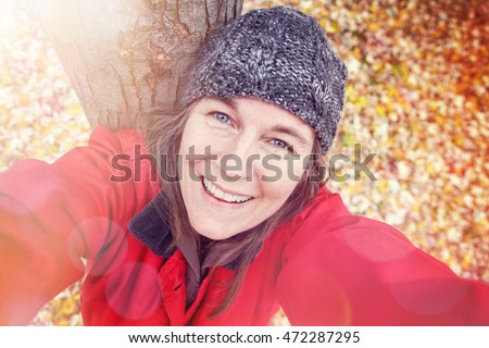 Middle aged woman taking a selfie in the fall