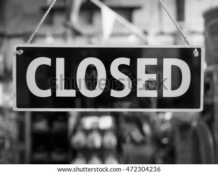 Closed sign in a shop showroom with reflections in black and white