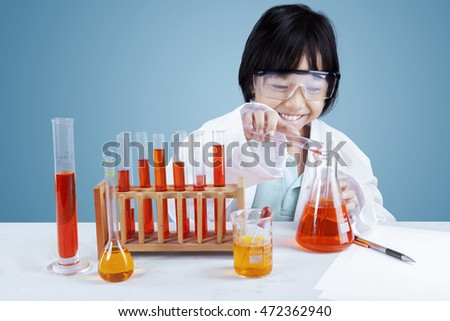 Picture of a little schoolgirl using chemical liquid to make experiments on the table
