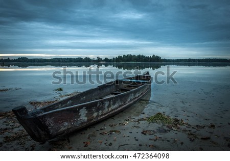 Lake view with boat. The wood boat on lake at sunset. Concept of loneliness, lacking direction, no leadership, rudderless, floating, listless or generally adrift without a goal. stillness calms Royalty-Free Stock Photo #472364098