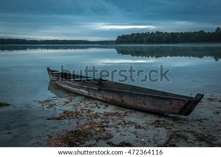 Lake view with boat. The wood boat on lake at sunset. Concept of loneliness, lacking direction, no leadership, rudderless, floating, listless or generally adrift without a goal. stillness calms Royalty-Free Stock Photo #472364116