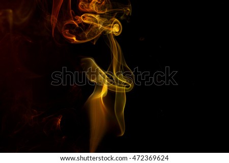 Abstract art. Color yellow red smoke from the aromatic sticks on a black background. Background for Halloween. Texture fog. Design element. The concept of aromatherapy.