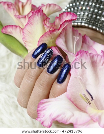 Beautifully manicured fingernails with gladiolus flowers in the background