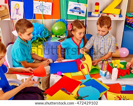 Large group children make from colored paper on table in school. Education of children in primary school. Top view of children and teacher.