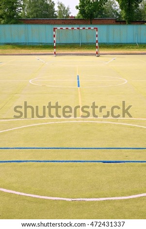 Empty outdoor handball playground, plastic hairy green surface on ground and white blue bounds lines. 
