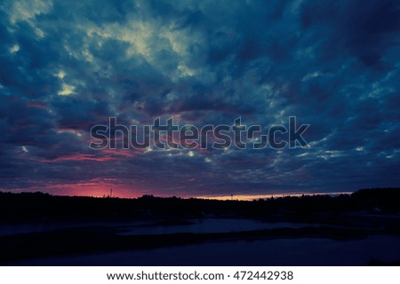 Colorful sunset sky with storm clouds and shining sun, tonal correction photo filter effect.                               
