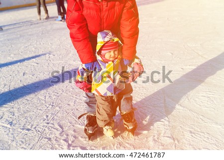 father and child learning to skate in winter