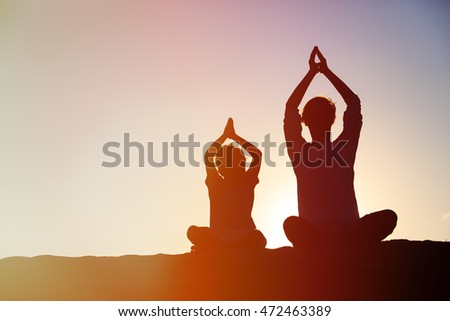 father and son doing yoga at sunset
