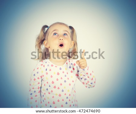 little girl wearing  pointing by forefinger to somewhere up isolated      
