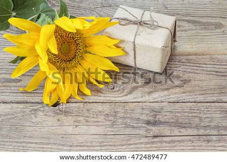 Background with yellow sunflowers and gift box on old wooden boards. Space for text.