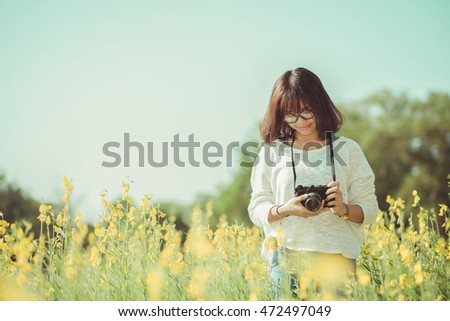 Young woman with camera in the Sunhemp garden , vintage tone