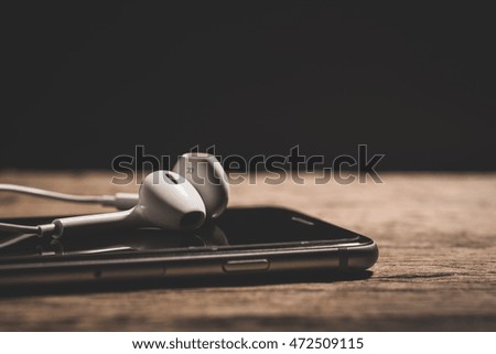  headphone and smartphone on wood table. 