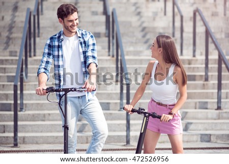 Cheerful friends riding scooters.