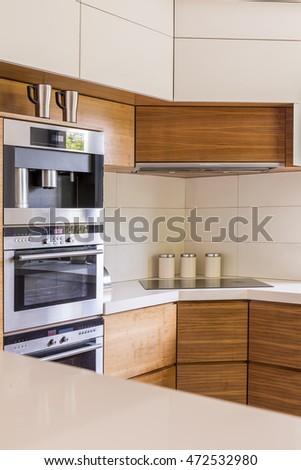 Cosy kitchen arranged in warm colours, with a set of ovens and an electric cooktop