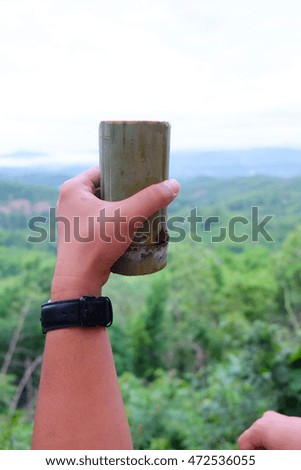 Bamboo cup with bamboo spoon in hand on nature background