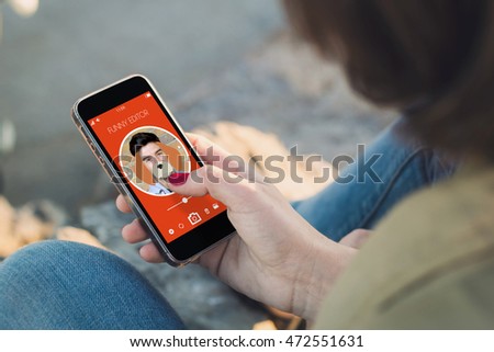 woman holding a smartphone and touching the screen to edit a picture. All screen graphics are made up.
