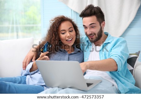 Young man and woman using credit card and laptop for online shopping