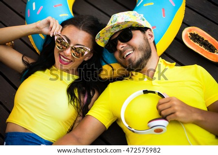 Lovely couple laying on the wooden floor,listening music on earphones.laughing happy,same t-shirts,couple love.pretty woman and her handsome man,love each other,enjoy summer,fruits,sunglasses couple 
