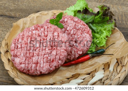 Raw burger cutlet with hot pepper and basil leaves
