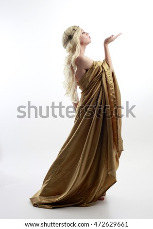 full length portrait of a blonde woman wearing a long gold draped grecian style gown. isolated on white background. Royalty-Free Stock Photo #472629661