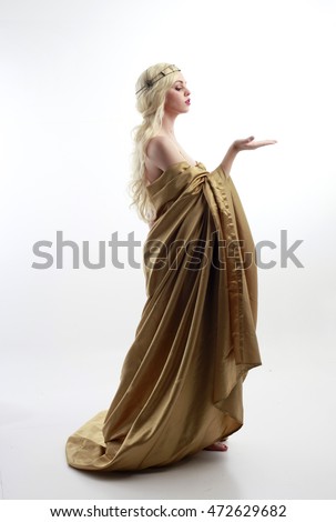 full length portrait of a blonde woman wearing a long gold draped grecian style gown. isolated on white background. Royalty-Free Stock Photo #472629682