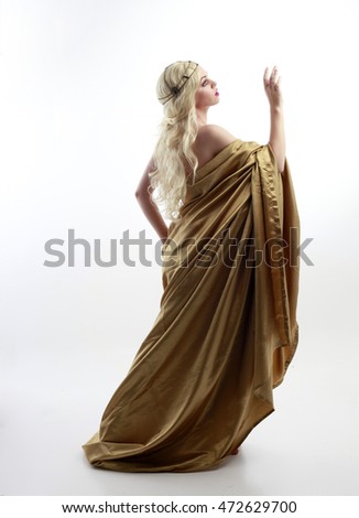 full length portrait of a blonde woman wearing a long gold draped grecian style gown. isolated on white background. Royalty-Free Stock Photo #472629700