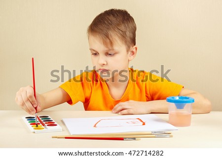Young artist in an orange shirt painting colors