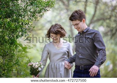 Curly lady and man in glasses look down while walking in the park