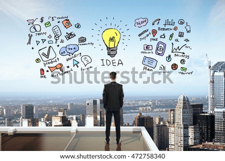 Businessman on rooftop looking at business idea sketch. City background. Success concept