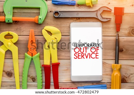 temporarily out of service concept with smart phone and handy tools pn wooden background