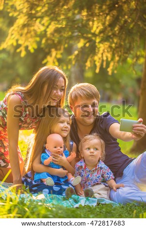 Happy family taking selfie sitting on the grass in a city park.