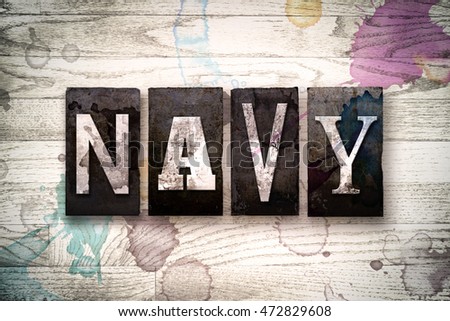 The word "NAVY" written in vintage dirty metal letterpress type on a whitewashed wooden background with ink and paint stains.