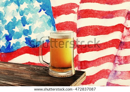 Glass of beer on wooden table. USA flag background.