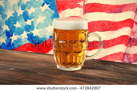 Glass of beer on wooden table. USA flag background.
