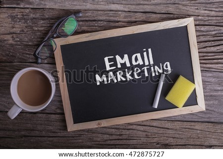 Email Marketing On blackboard with cup of coffee, with glasses on wooden background