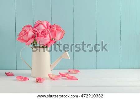 Withered pink rose flowers at watering can on white and blue wooden background with vintage tone, Vintage rose Royalty-Free Stock Photo #472910332