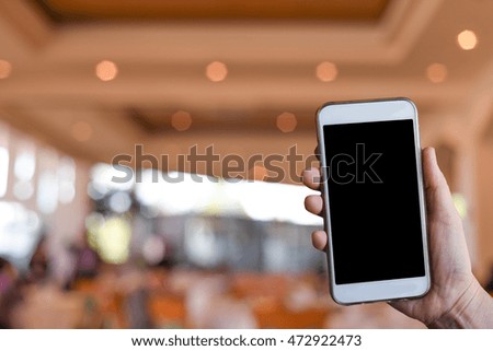 hand using smartphone for doing business or banking or buying online on blur shopping mall background.