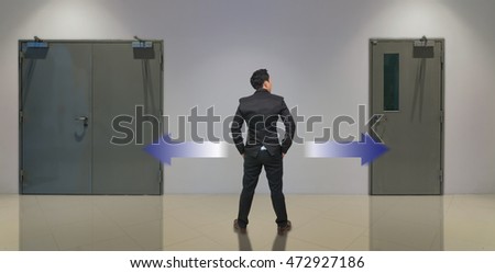 Businessman standing in doubt,thinking the two different choices indicated by arrows pointing in opposite direction, business decision concept