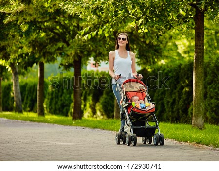 walking Mother with baby carriage Royalty-Free Stock Photo #472930741