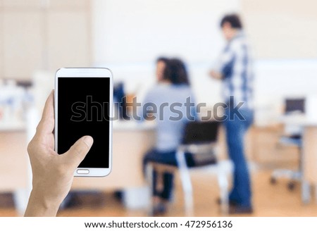 Man use mobile phone, blur image of employees in the office are talking as background.