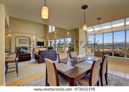 Open floor dining room with wooden table set and pendant lights. Family room view. Northwest, USA