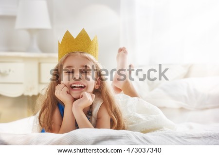 Cute little girl in a princess costume. Pretty child preparing for a costume party. Beautiful queen in gold crown. Royalty-Free Stock Photo #473037340