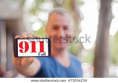 Man hand holding emergency call smartphone. Handsome  modern man shows mobile smart phone blank screen with EMERGENCY 911 CALL option. Shot with third-person view.