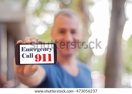 911. Handsome  modern man shows mobile smart phone blank screen with EMERGENCY CALL option. Shot with third-person view.