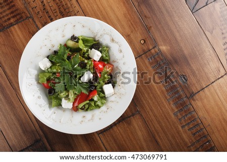 Greek salad on a white plate. top view. wooden background.