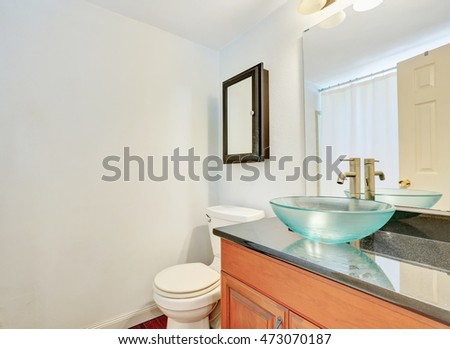 White interior of bathroom with wooden vanity and glass blue washbasin. Northwest, USA